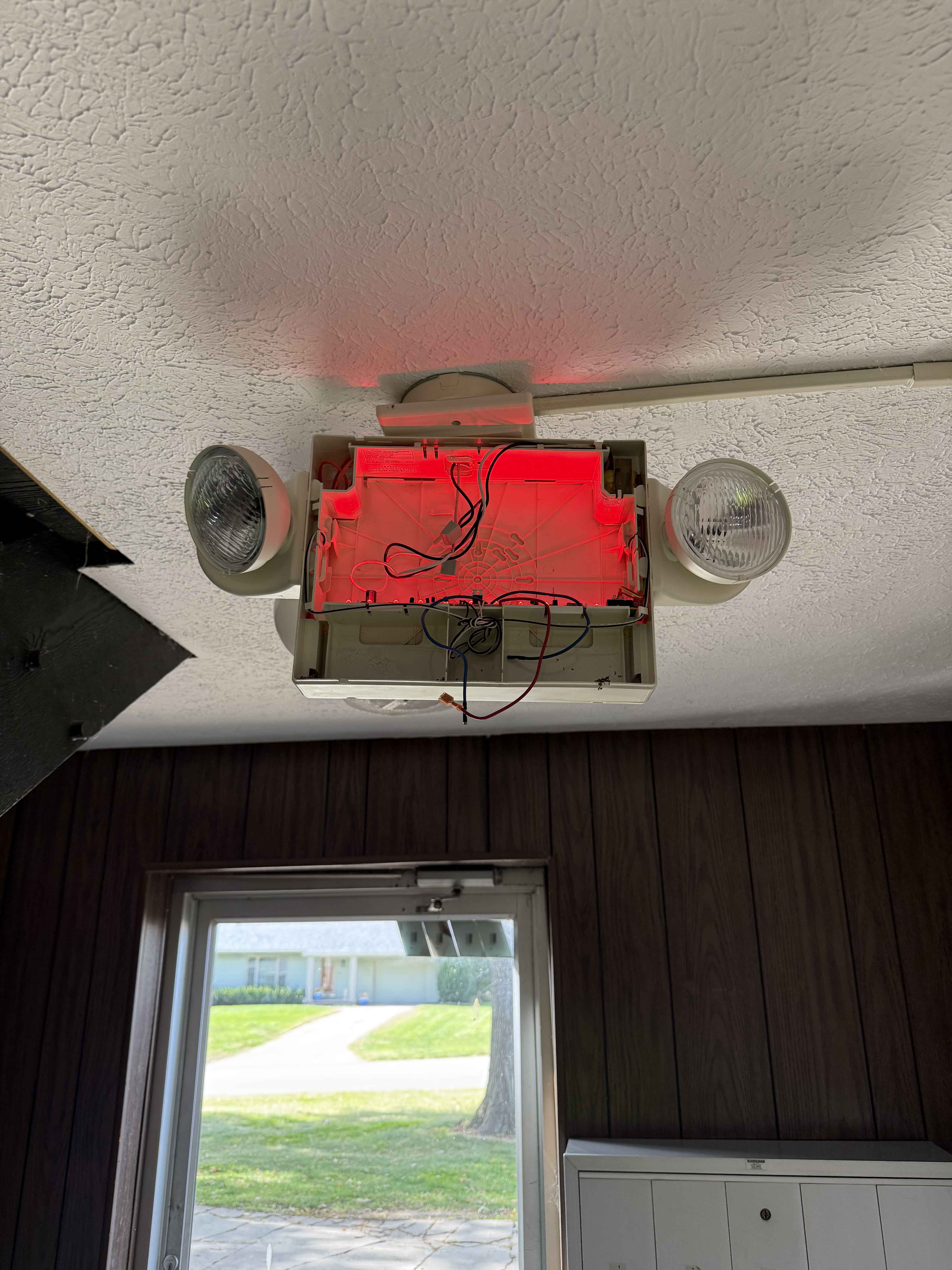 Old exit and emergency light fixture with exposed wiring and outdated design