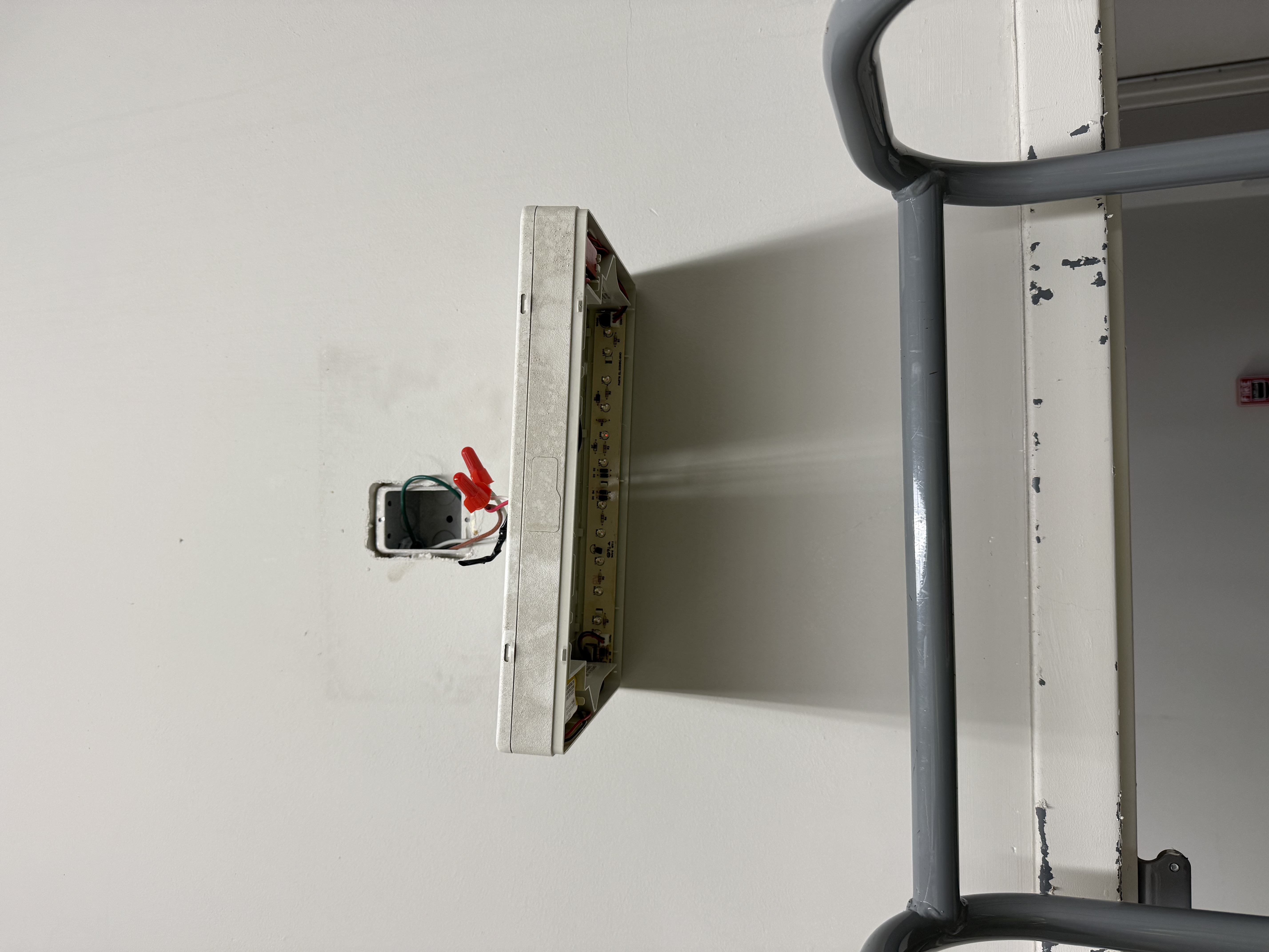 Outdated exit and emergency light being removed with exposed wiring