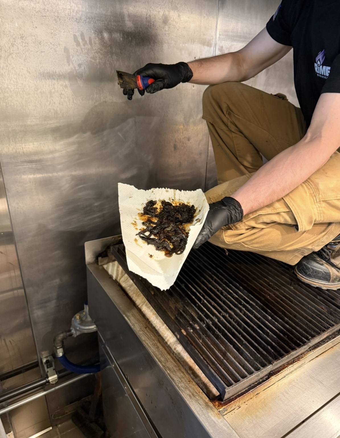 Prime Fire Services technician performing deep clean on kitchen exhaust system